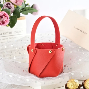 Detail of red leather mini gift bucket with gold rivets and lychee texture for weddings