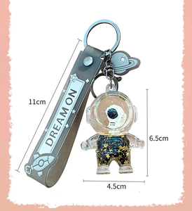 Detailed view of astronaut liquid keychain with golden glitter and Dream On silicone strap