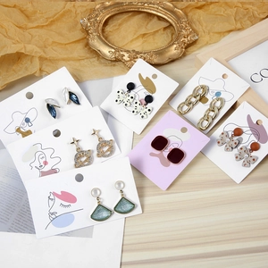 Close-up of assorted jewelry earrings on artistic paper cards with gold frame background