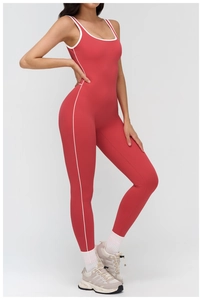 Side view of red yoga jumpsuit featuring white contrast piping and a deep U-neck design