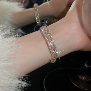 Detail of luxury pink zircon stones on gold multi-layer bracelet worn by model in party lighting