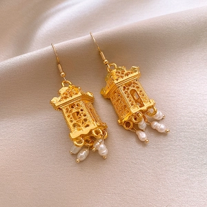 Makroaufnahme goldener Laternenohrringe mit filigraner Schnitzerei und Perlenquasten
