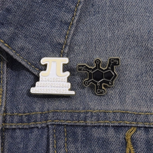 Creative enamel pins featuring Pi symbol and Caffeine molecule on blue denim fabric background