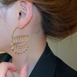 Gold semi-circle drop earrings with rectangular zircon tassels on a model