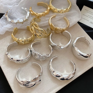 Detailed view of mixed gold and silver open cuff bracelets with irregular textures