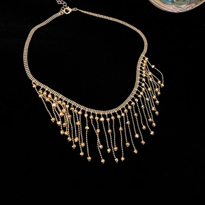 Elegant gold tassel choker necklace with bead fringe accents on a black background