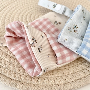 Detail of floral and plaid fabric nursing pen pouch with white plastic snap button