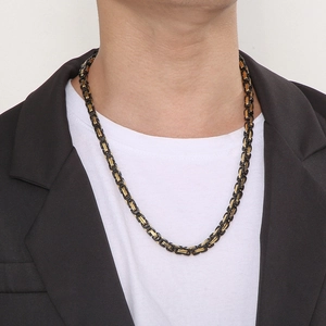 Detail of men's Byzantine chain necklace in gold and black steel on a male model