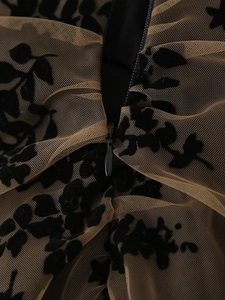 Détail du tissu en maille avec fleurs floquées noires et fermeture éclair au dos