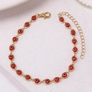 Detailed close-up of golden copper chain bracelet with red Evil Eye beads and lobster clasp