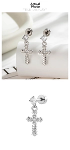 Detail of silver gothic cross earrings with sparkling zircon stones and relief texture