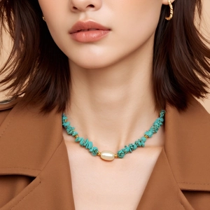 Close-up of bohemian turquoise gravel necklace with pearl and gold beads on model