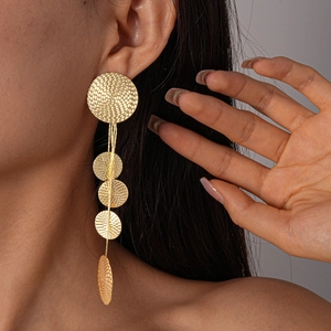 Close-up of golden geometric round textured metal tassels earring on a model