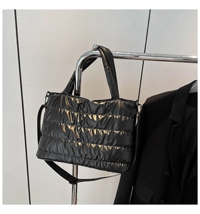 Detail of black quilted puffer bag showing glossy finish and metal strap hardware