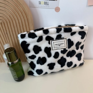 Plush cow print coin purse with zipper and Time to Party label on a white table