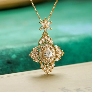 Exquisite gold floral star pendant necklace with zircons and crystals on green background