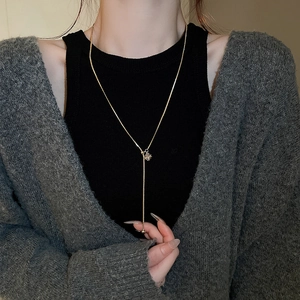 Detail of gold Y-necklace with square zircon slider and snake chain on a model