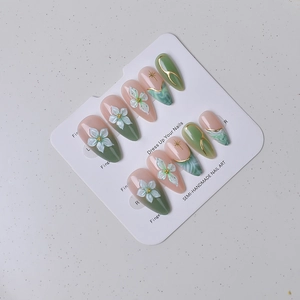 Detail of semi-handmade emerald green almond nails with 3D floral art and gold foil accents