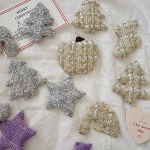 Macro view of handmade tweed Christmas ornaments including stars and stockings on white linen