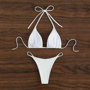 Detailed view of white ribbed fabric halter bikini set on dark wood background