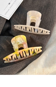 Detailed view of handmade pearlescent white and marble pattern acrylic hair claws