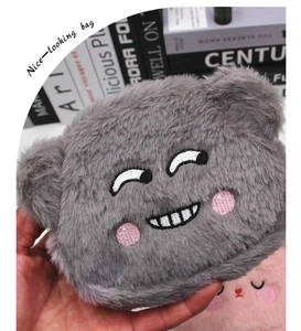 Close-up of grey plush bear pouch with embroidered smile face and soft texture detail