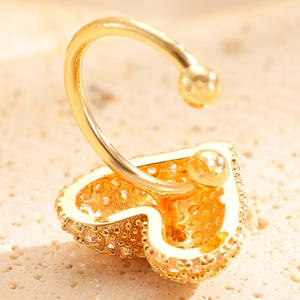 Macro shot of gold navel ring with heart-shaped zircon pavé and polished spheres