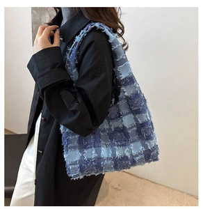Detail of blue quilted tote bag with fringe edges and plaid tweed texture on model