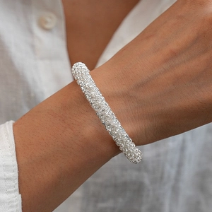 Gros plan d'un bracelet géométrique argenté serti de strass brillants porté au poignet