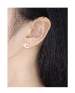 Close-up of model wearing textured silver moon stud earrings with zircon stones