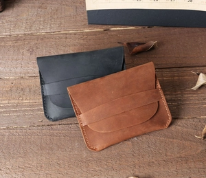 Handcrafted minimalist leather card holders in black and brown over a rustic wood desk