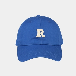 Dettaglio del cappellino in cotone blu reale con toppa con lettera R ricamata in spugna
