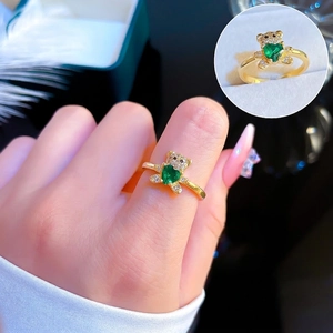 Detail of a gold plated bear ring with a green heart-shaped gem and sparkling zircons