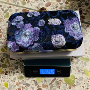 Detailed macro view showing embroidery and weight of the blue floral evening clutch bag