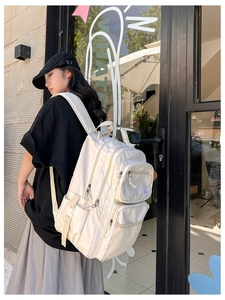 Side view of cream-white nylon backpack featuring multiple zipper layers and mesh pocket
