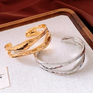 Dettaglio di bracciali doppi irregolari placcati in oro 18 carati e argento su vassoio
