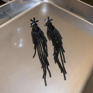 Detail of long black fringe earrings with flower stud and sparkling rhinestones