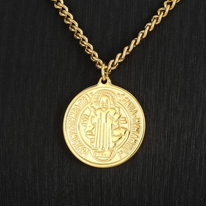 Macro detail of gold Saint Benedict religious medal pendant on thick chain