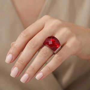 Gros plan d'une bague en acier argenté avec un grand cristal rouge sur une main