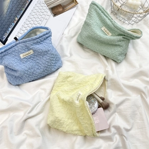 Detailed view of bubble textured cosmetic bags in blue, green and yellow with zip closure