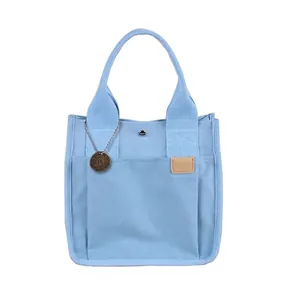 Borsa tote minimalista in tela celeste con manici larghi e ciondolo in metallo vintage