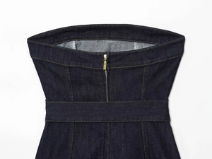 Détail du haut en jean indigo foncé avec fermeture éclair dorée et coutures jaunes