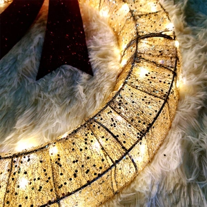 Macro shot of festive Christmas wreath with gold glitter mesh and warm LED string lights