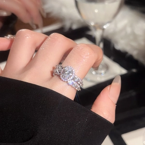 Detail of elegant oval-cut zircon halo ring and pave band on hand with luxury lighting