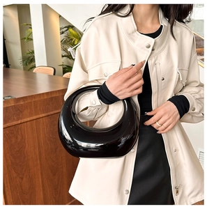 Polished black patent leather crescent handbag with reflective glossy finish in a chic look
