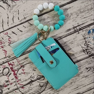 Macro shot of mint green leather card wallet with silicone beaded bracelet and tassel