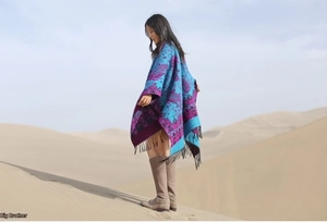 Detailed view of paisley patterned shawl with black fringes in a desert landscape setting