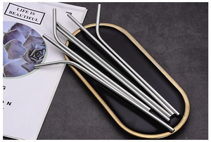 Detailed view of 5 silver curved stainless steel straws on a decorative black and gold tray