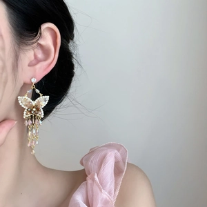 Vue latérale macro de longues boucles d'oreilles papillon avec zircons roses sur un modèle