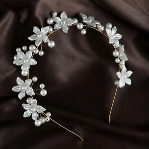 Close-up of pearl flower headband with gold wire detailing on dark silk fabric